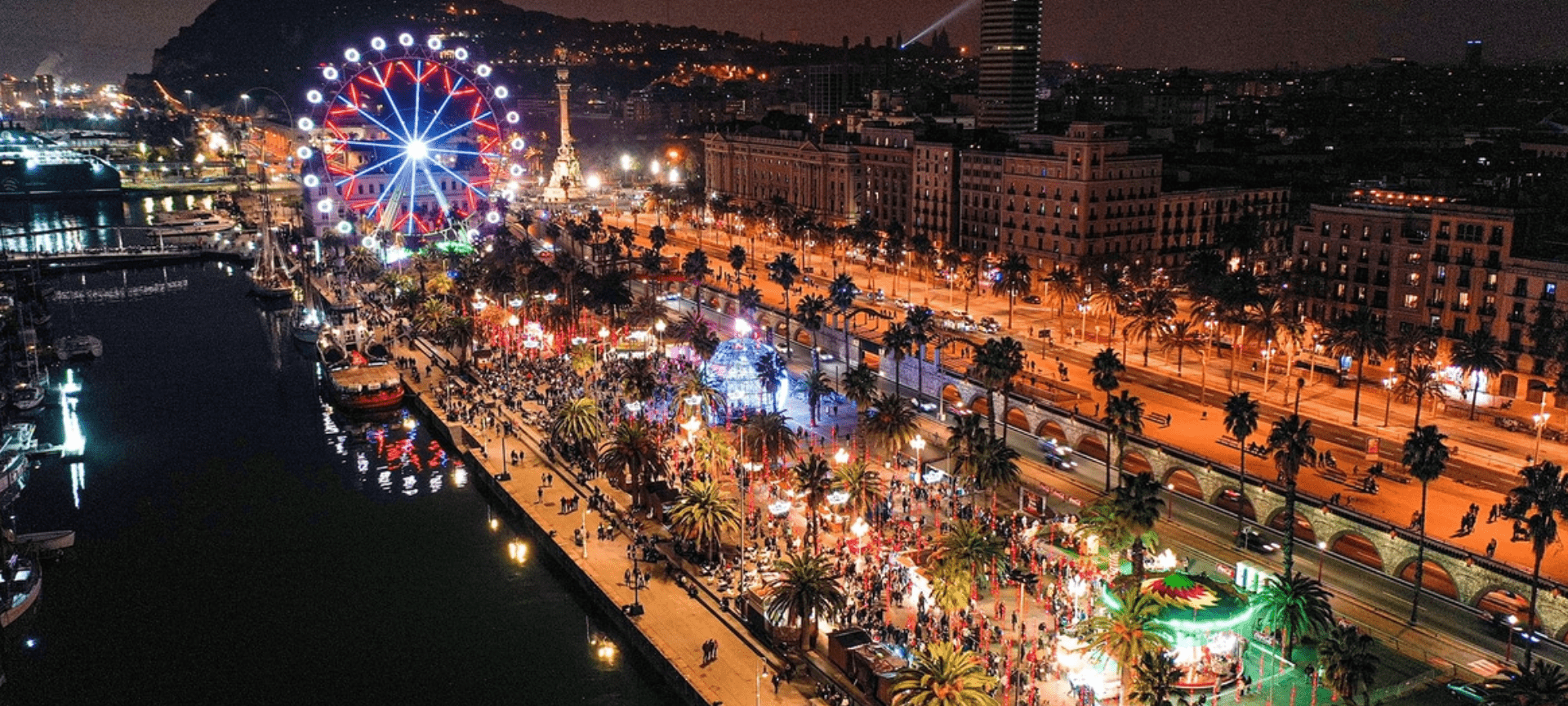 Aerial drone view of the Christmas Fair (Fira de Nadal) at Barcelona&rsquo;s Port Vell, featuring the illuminated Ferris wheel, festive stalls, and a lively holiday atmosphere by the sea